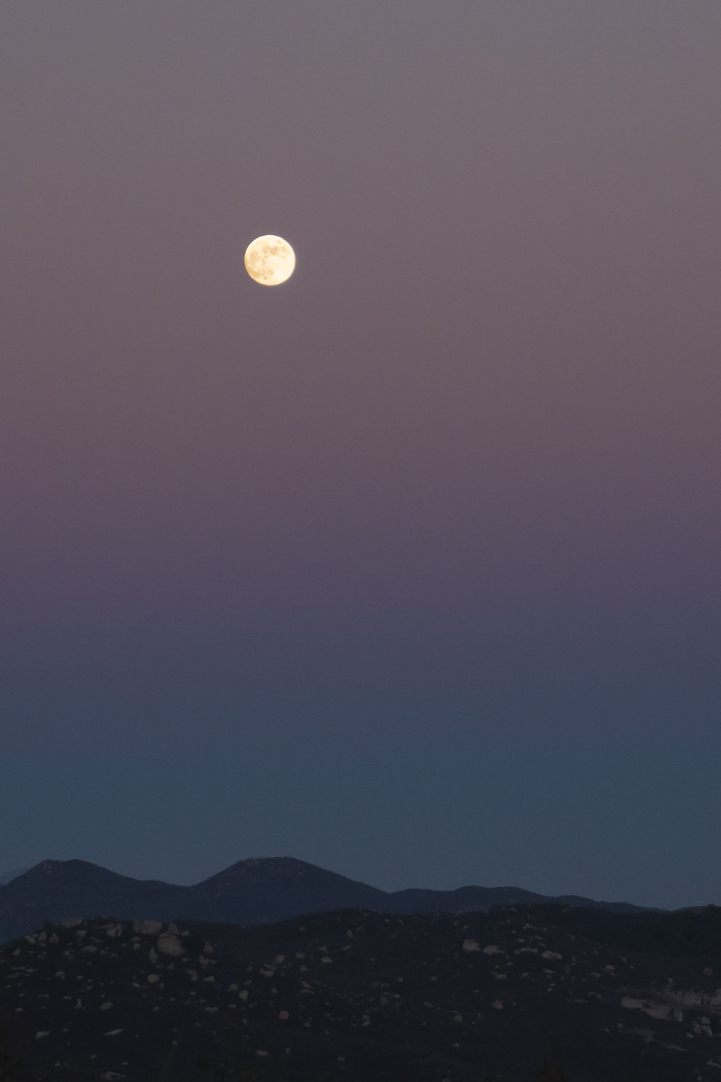 full moon in sunset sky over mountains